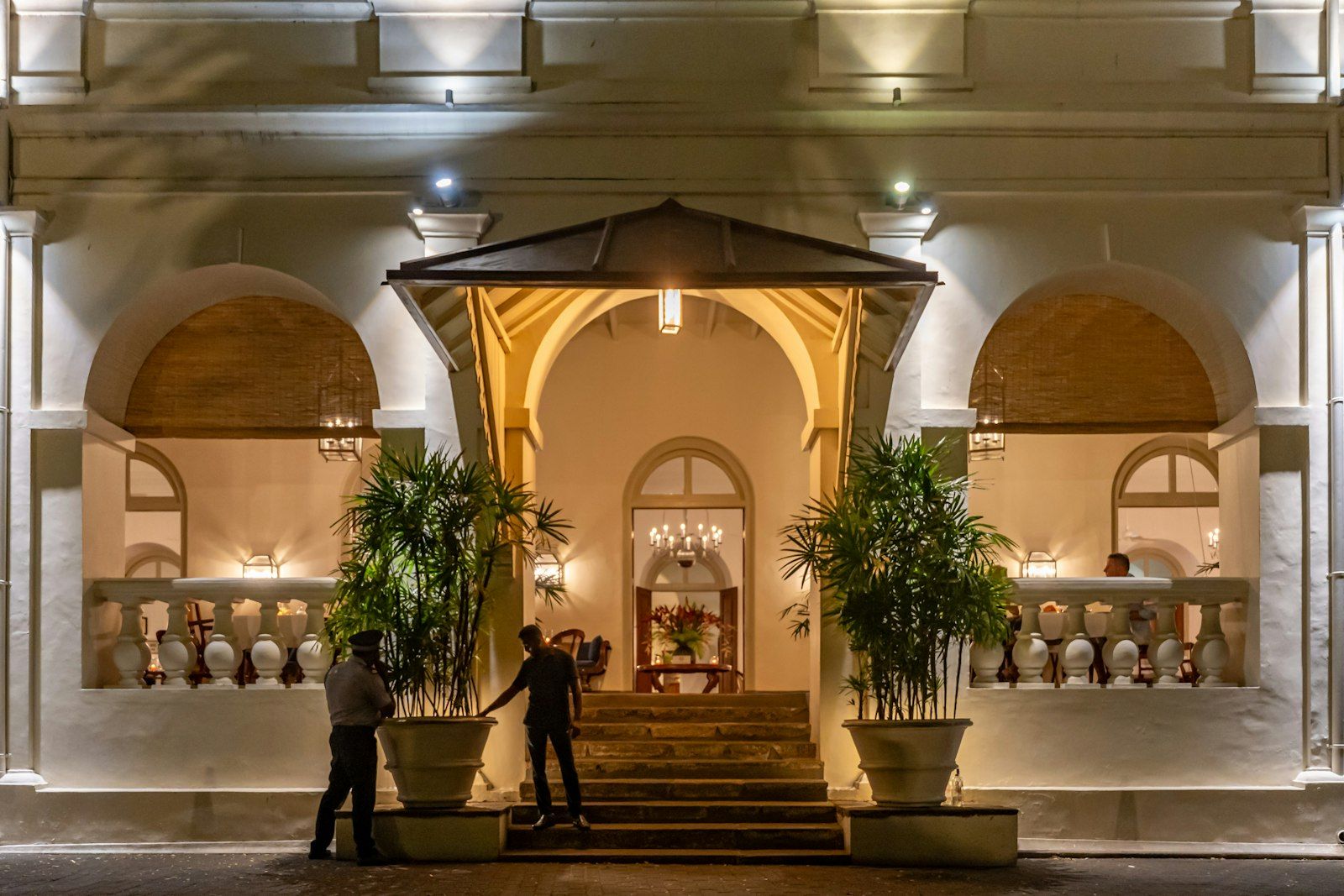 Entrée d’un établissement éclairée le soir, sous les arcades.