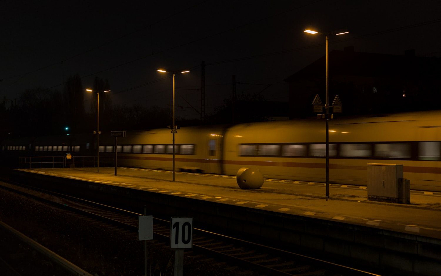 Train à l’arrêt le long d’un quai éclairé, de nuit.