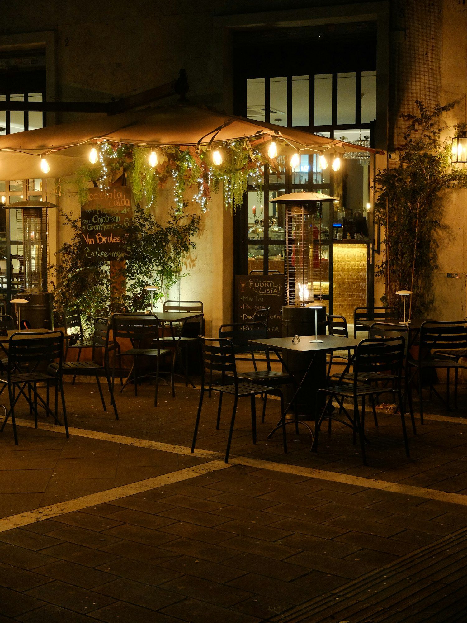 Terrasse de café éclairée de guirlandes, le soir.